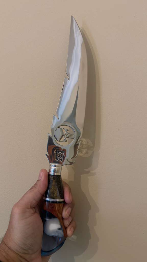 Hand holding a knife with a decorative handle against a plain background